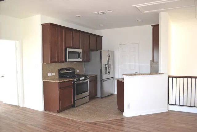 a kitchen with stainless steel appliances granite countertop a refrigerator stove top oven and sink