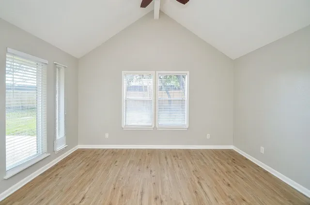 an empty room with wooden floor and windows