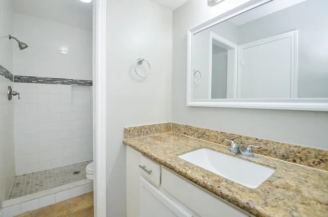 a bathroom with a granite countertop sink and a mirror