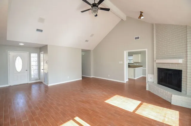 a view of a livingroom with a fireplace a ceiling fan and wooden floor