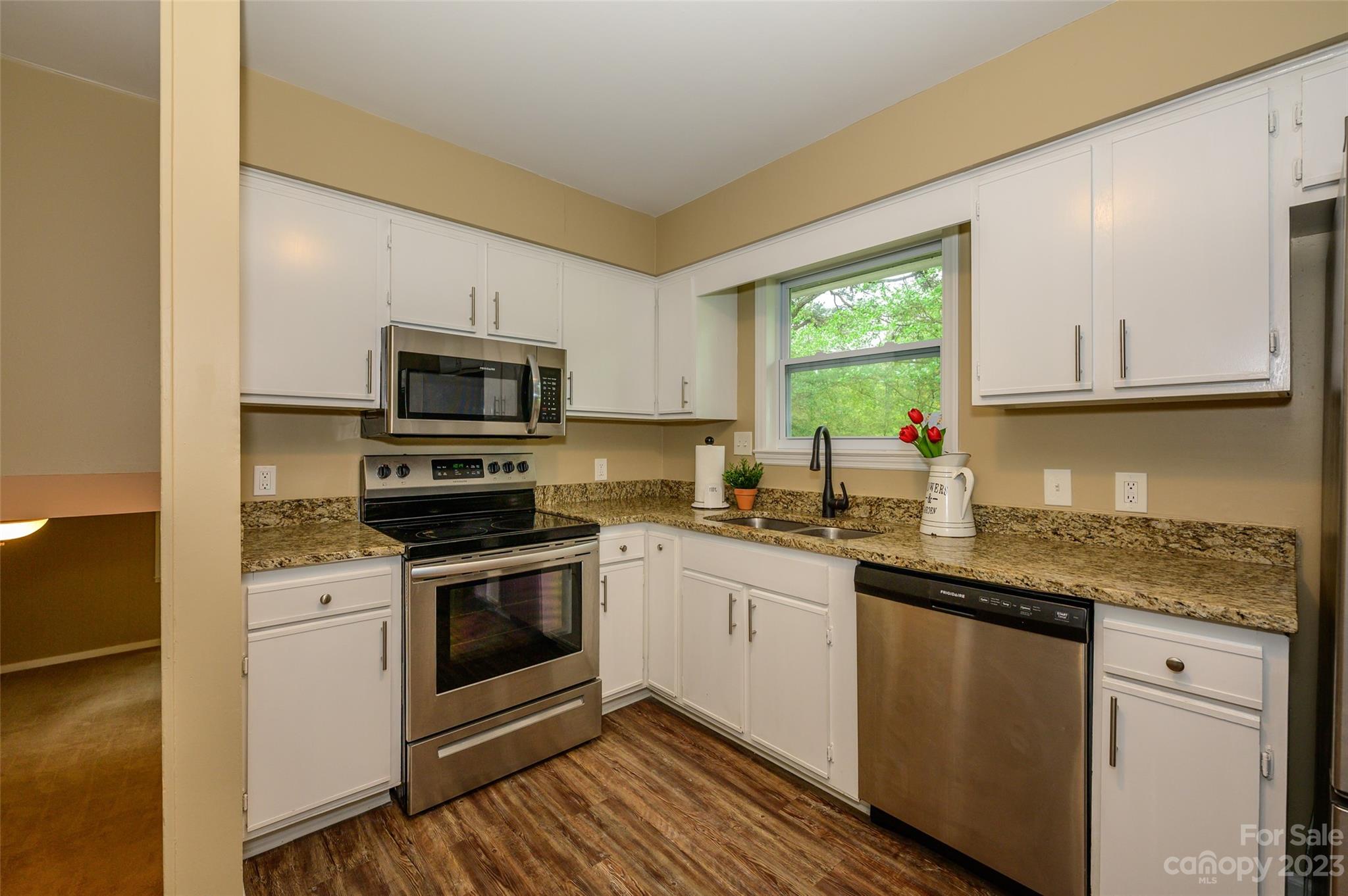 16079 Molokai Drive Tega Cay, SC 29708 - Photo 16 of 41 a kitchen with granite countertop white cabinets appliances a window and a sink