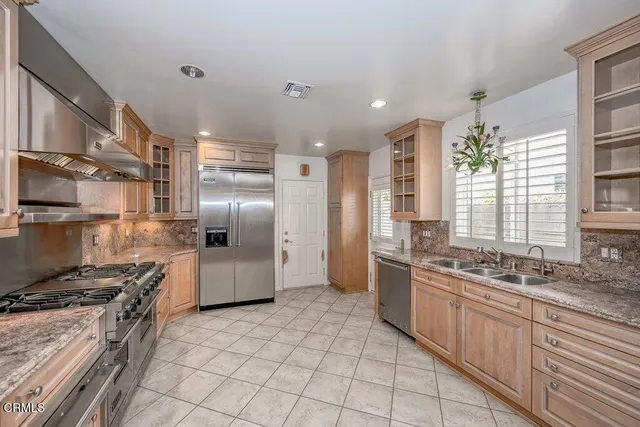 a kitchen with stainless steel appliances granite countertop a stove a sink and a refrigerator
