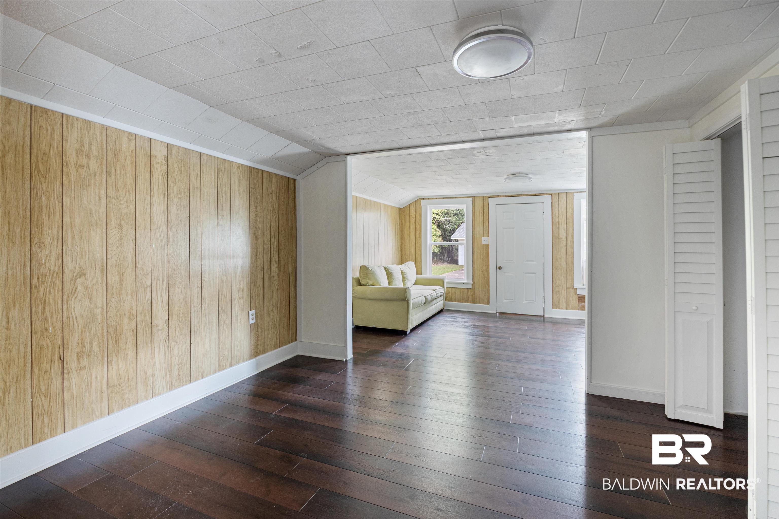 112 South Juniper Street Foley, AL 36535 - Photo 17 of 64 Unfurnished room featuring wood walls, dark wood-style floors, and lofted ceiling
