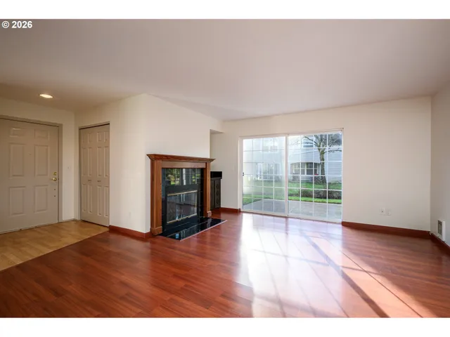 a view of an empty room with glass door and wooden floor