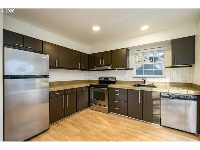 a kitchen with stainless steel appliances granite countertop a refrigerator stove top oven a sink and dishwasher