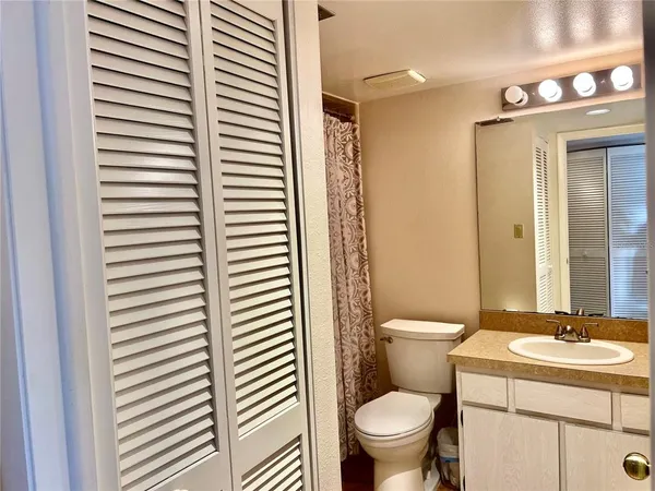 a bathroom with a granite countertop toilet a sink and a mirror