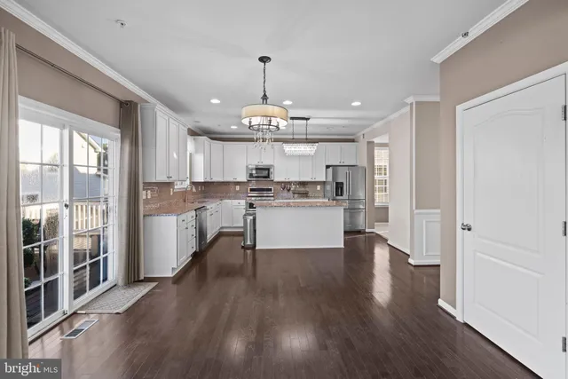 a kitchen with stainless steel appliances granite countertop a refrigerator a sink dishwasher a stove and white cabinets with wooden floor