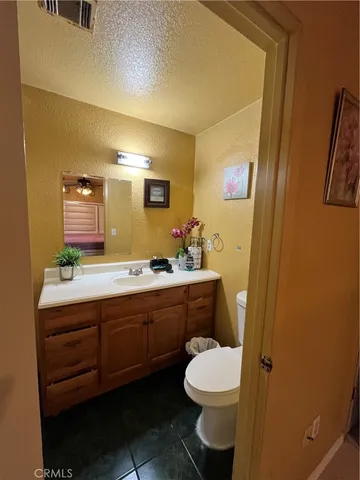 a bathroom with a granite countertop toilet sink and mirror