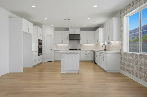 a large white kitchen with granite countertop a stove top oven a sink and a refrigerator