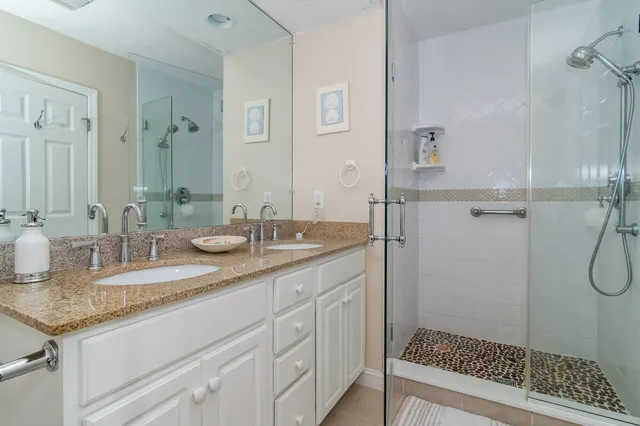 a bathroom with a granite countertop sink a mirror and shower