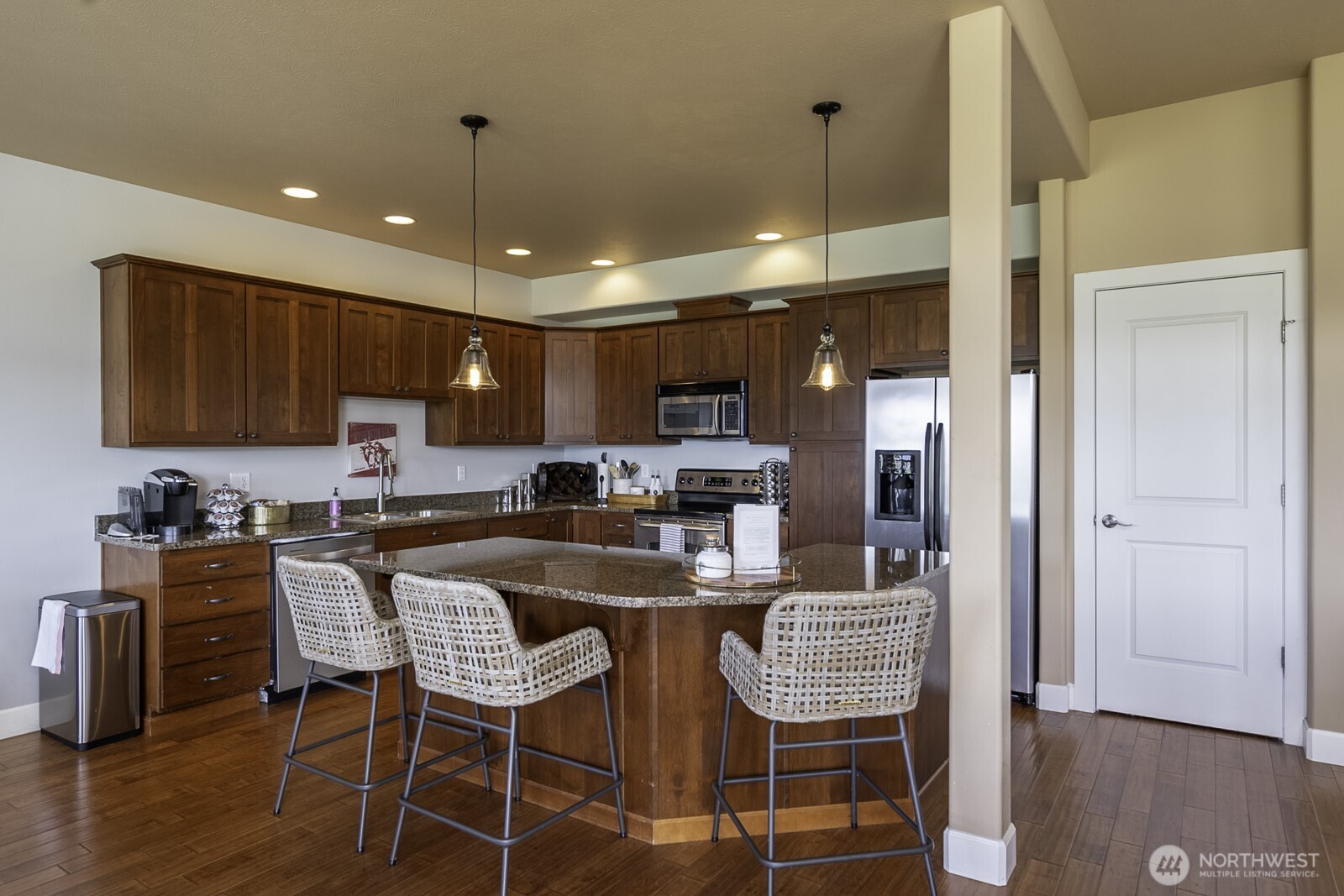 23466 Sunserra Loop Quincy, WA 98848 - Photo 13 of 40 a kitchen with stainless steel appliances granite countertop a refrigerator a stove a sink dishwasher and a dining table with wooden floor