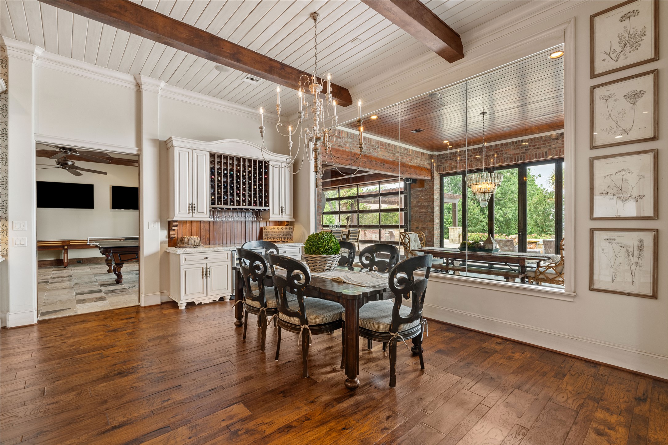 12349 Longmire Trace Conroe, TX 77304 - Photo 10 of 48 Elegant dining room with exposed beams, brick accents, built-in wine storage, and wall-to-wall glass doors.