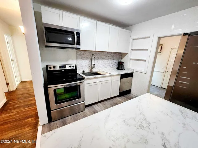 a kitchen with stainless steel appliances a stove microwave sink refrigerator and cabinets