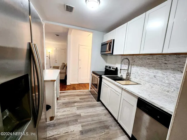 a kitchen with granite countertop white cabinets and stainless steel appliances