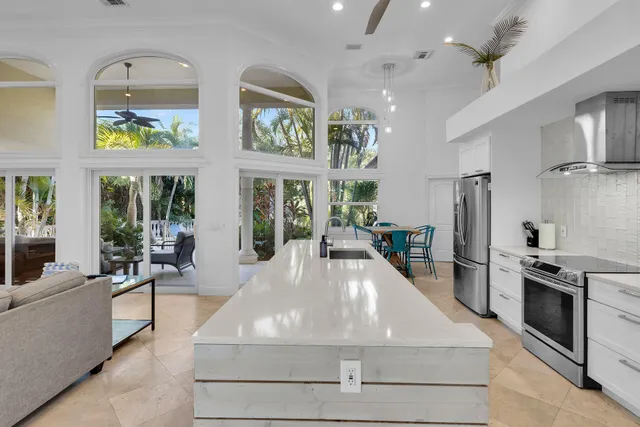a large white kitchen with stainless steel appliances granite countertop a stove and a refrigerator