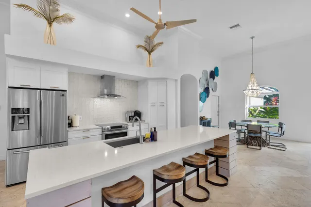 a kitchen with granite countertop a refrigerator a stove a dining table and chairs with wooden floor