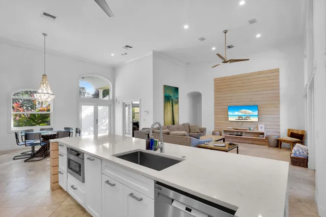 a large kitchen with a large counter top space a sink stainless steel appliances and furniture