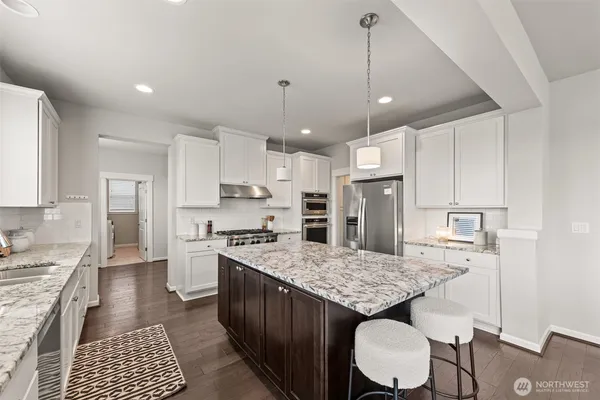 a kitchen with kitchen island granite countertop wooden cabinets and refrigerator