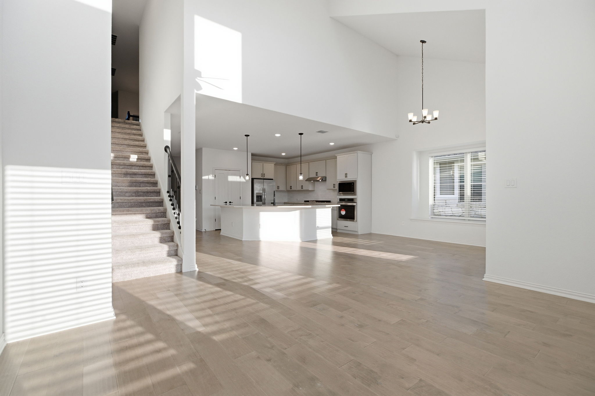 13720 Jon Ryan Road Manor, TX 78653 - Photo 13 of 31 A luminous living space features towering ceilings, warm hardwood flooring, and an open-concept kitchen.