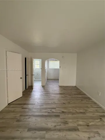 a view of empty room with window and wooden floor