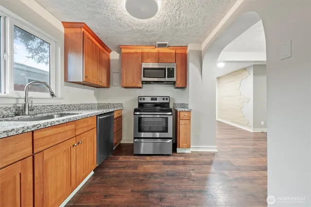 a kitchen with granite countertop a sink and a stove top oven