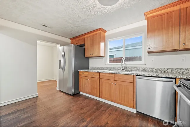 a kitchen with granite countertop stainless steel appliances a sink and a counter space