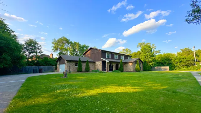 a view of a house with a big yard potted plants and large tree