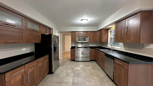 a large kitchen with stainless steel appliances kitchen island granite countertop a stove a sink and a refrigerator