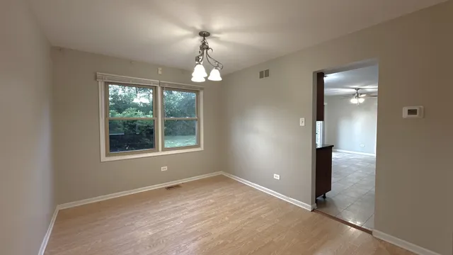 an empty room with wooden floor mirror and window