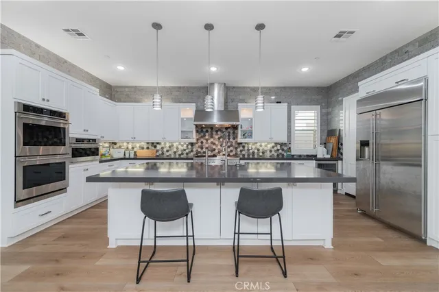 a kitchen with stainless steel appliances granite countertop a stove a sink a microwave a refrigerator and chairs