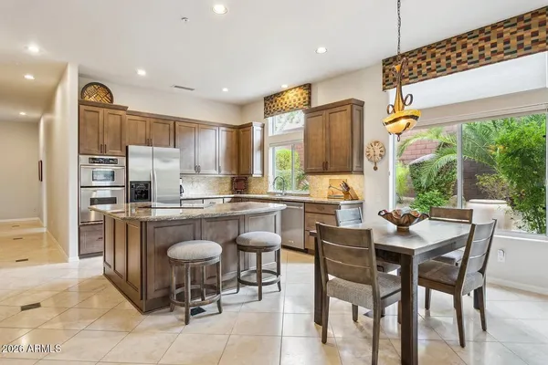 a kitchen with a dining table chairs and refrigerator