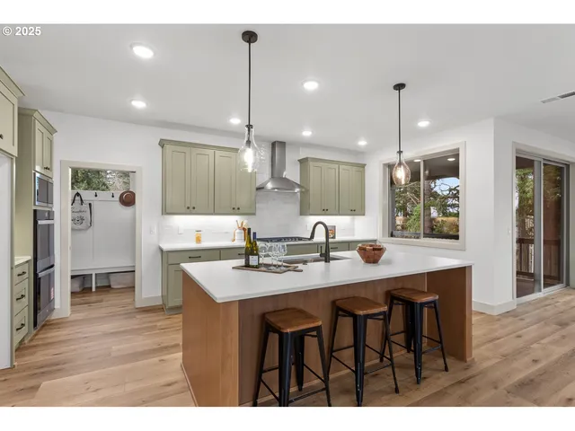 a open kitchen with stainless steel appliances granite countertop a sink dishwasher a stove and a dining table with wooden floor