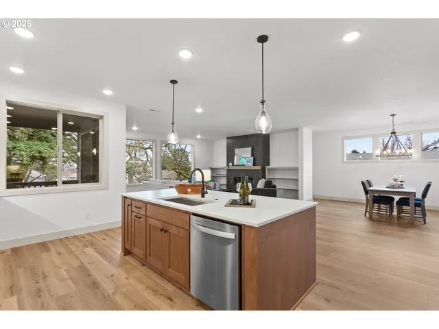 a kitchen with stainless steel appliances granite countertop a sink a stove and a wooden floors
