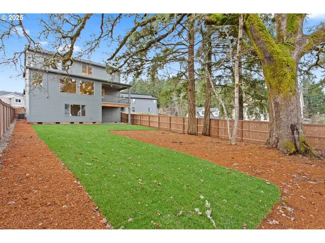 a view of a house with backyard and a tree