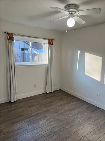 an empty room with wooden floor closet and windows