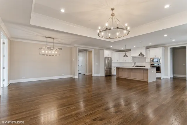 a view of an empty room and kitchen with kitchen chandelier