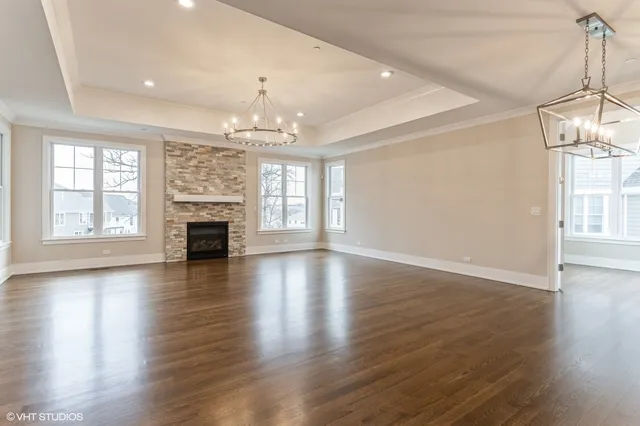 an empty room with wooden floor fireplace and windows