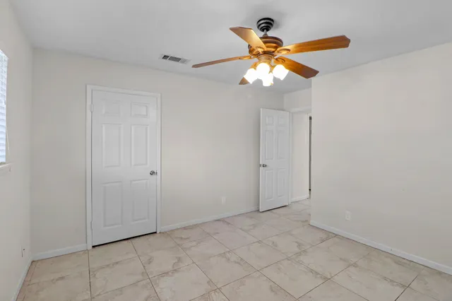 a view of an empty room and cabinet with a ceiling fan