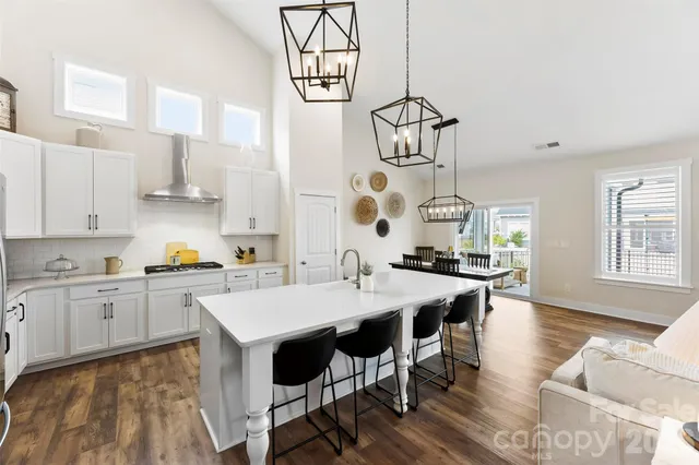 a kitchen with stainless steel appliances a white table chairs and a refrigerator