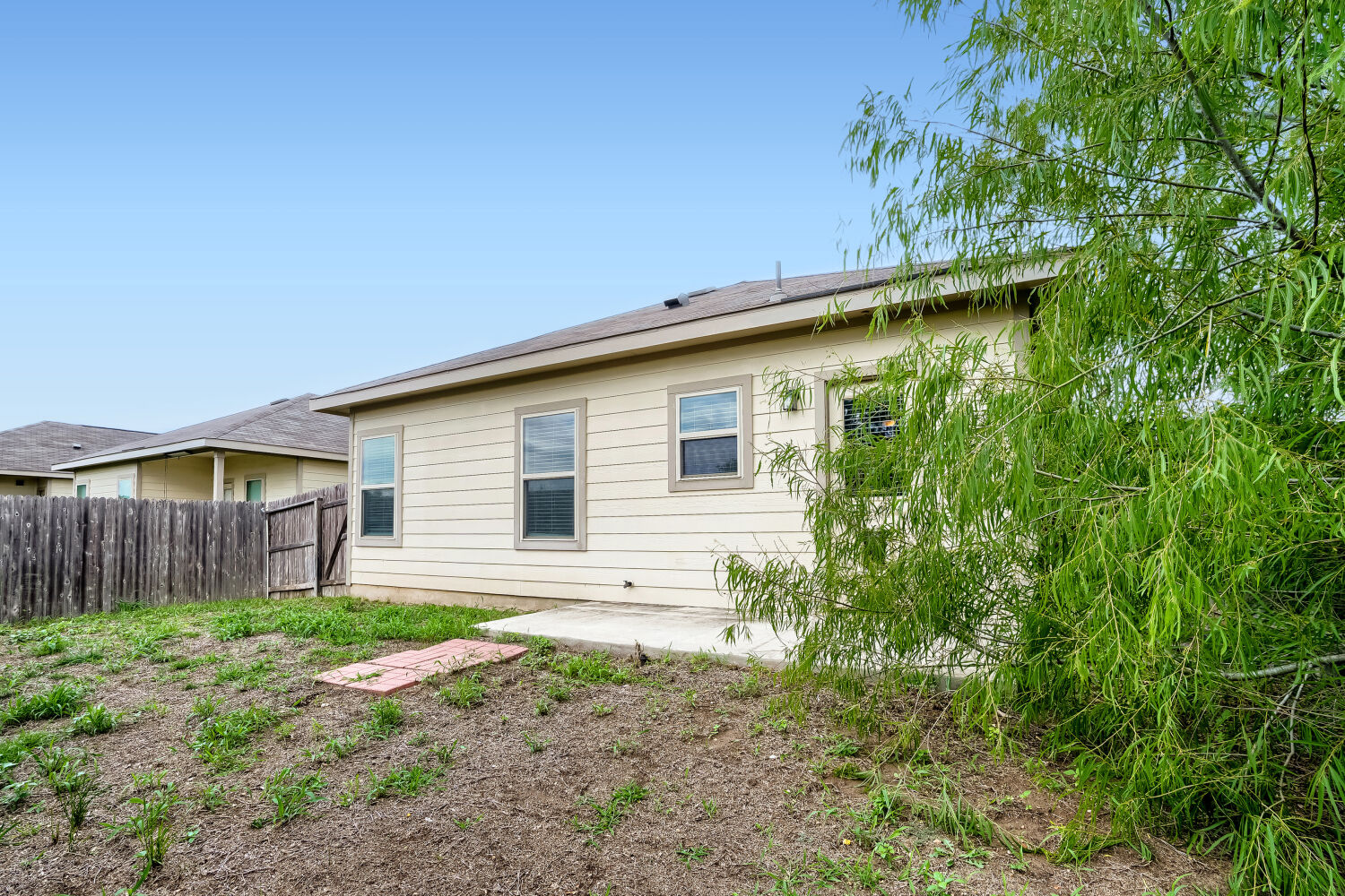 2420 Ranger Pass Seguin, TX 78155 - Photo 27 of 28 Rear exterior featuring light-colored horizontal siding, multiple windows, and a concrete patio