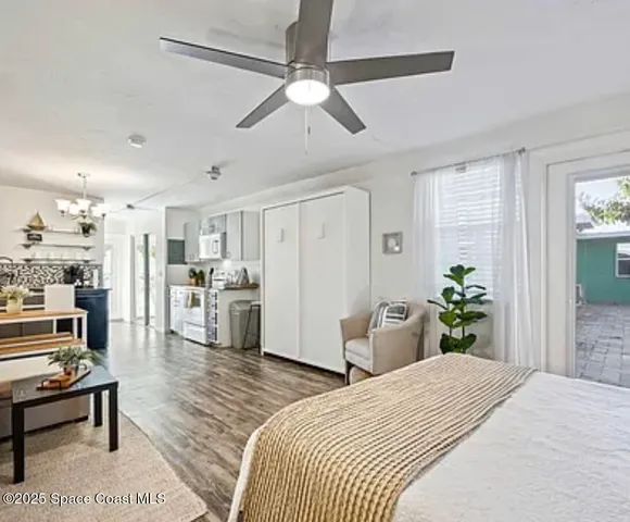 a bedroom with a bed dresser and a view of kitchen