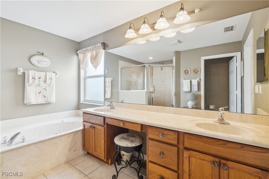 9475 Silver Pine Loop Fort Myers, FL 33967 - Photo 27 of 34 a spacious bathroom with a granite countertop sink mirror and bathtub