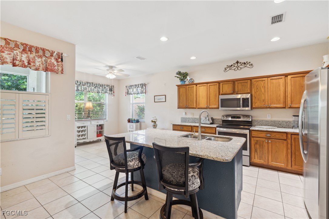 9475 Silver Pine Loop Fort Myers, FL 33967 - Photo 7 of 34 a kitchen with stainless steel appliances granite countertop a stove a sink a microwave a dining table and chairs