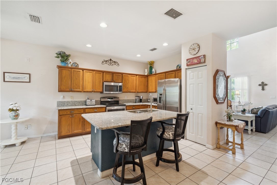 9475 Silver Pine Loop Fort Myers, FL 33967 - Photo 8 of 34 a kitchen with stainless steel appliances kitchen island granite countertop a table chairs and a refrigerator