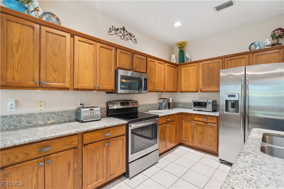 9475 Silver Pine Loop Fort Myers, FL 33967 - Photo 9 of 34 a kitchen with stainless steel appliances granite countertop a sink a stove a refrigerator cabinets and a window