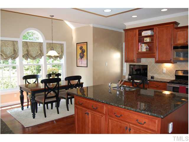 9219 Stone Mountain Road Raleigh, NC 27613 - Photo 8 of 25 Cooking is a delight in the gourmet kitchen that offers stainless steel appliances, granite counters, a center island with veggie sink, a tile backsplash, and a Bill desk. Kitchen