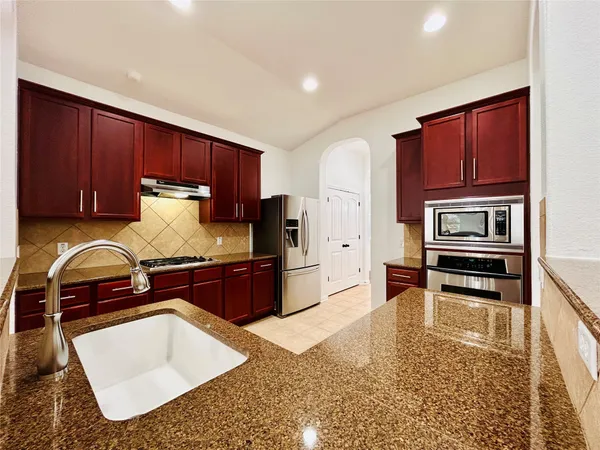 a kitchen with granite countertop a stove top oven microwave and cabinets