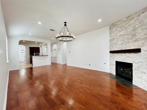 a view of empty room with kitchen and fireplace