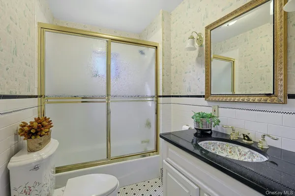 a bathroom with a granite countertop sink a toilet a mirror and shower