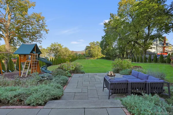 a view of a patio with table and chairs potted plants and a large tree